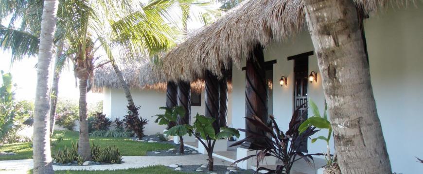 palm thatch entrance to home with large stained carved wood posts