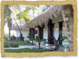 palm thatch entrance to home with large stained carved wood posts